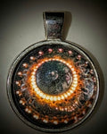 Macro photography pendant of an intricate botanical chandelier detail from the Washington State Capitol, featuring a symmetrical 'eye' pattern in a stainless steel round frame.