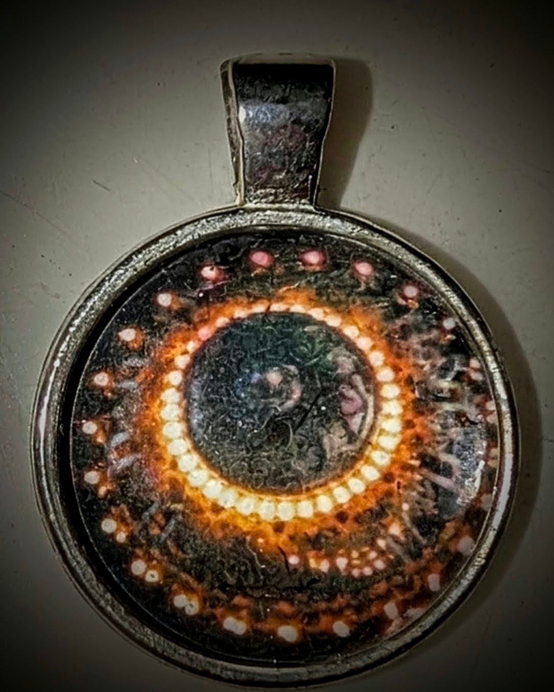 Macro photography pendant of an intricate botanical chandelier detail from the Washington State Capitol, featuring a symmetrical 'eye' pattern in a stainless steel round frame.